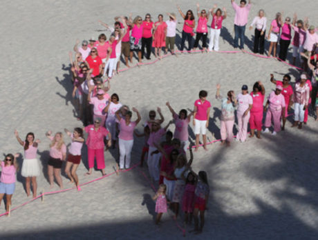 Human pink ribbon in the sand highlights breast cancer awareness